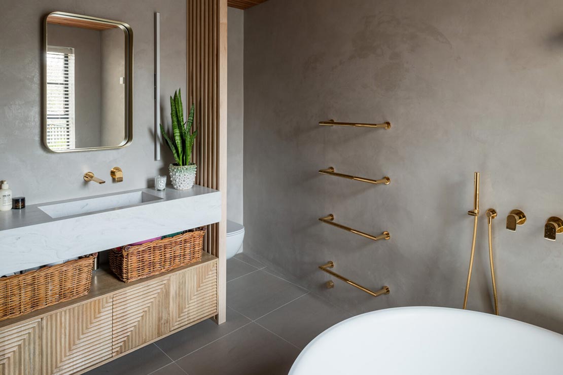 dark beige bathroom with sink and freestanding tub with gold faucets