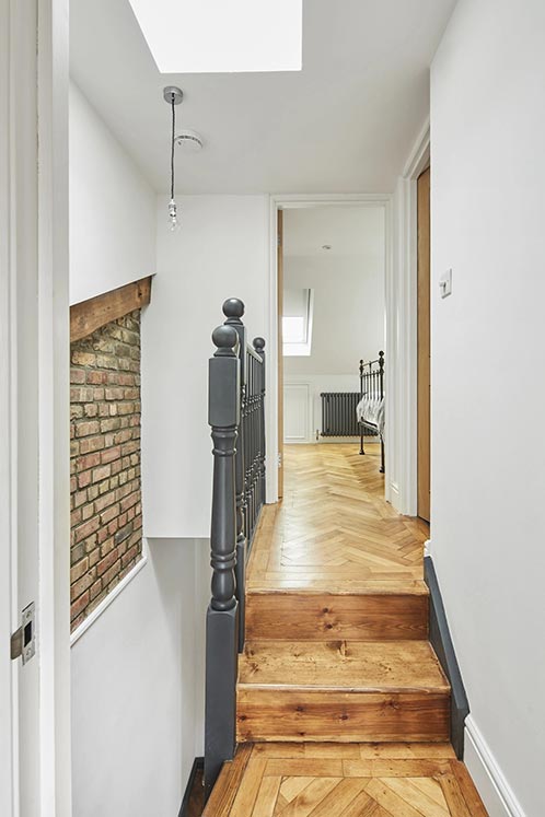 upstairs hallway with wooden flooring leading to white bedroom