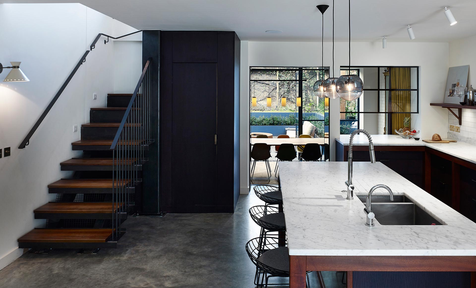 open plan modern kitchen with dining area and wooden and black staircase in Sussex Gardens London