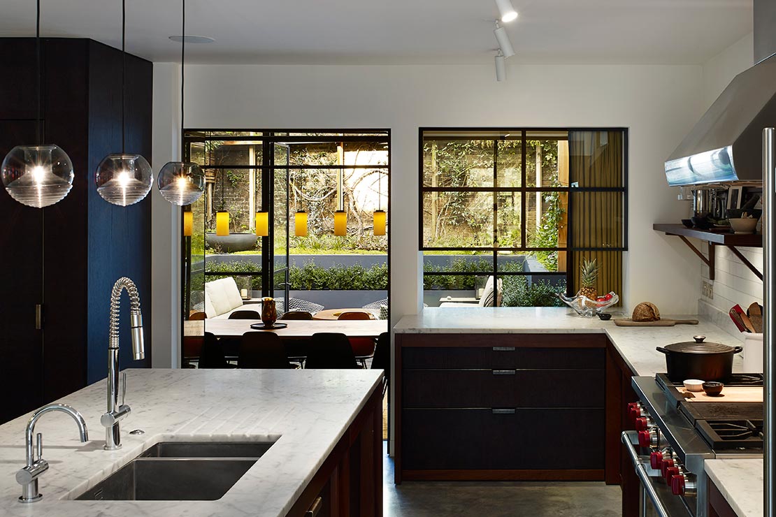 kitchen with marble top kitchen island, gas stove top and black cabinets