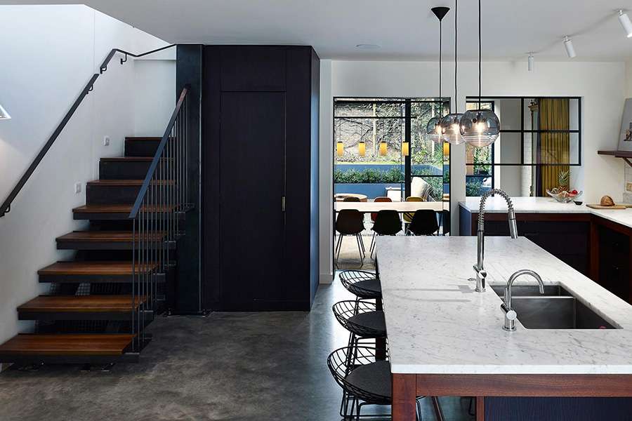 Open plan modern kitchen with dining area and wooden and black staircase in Sussex Gardens, London