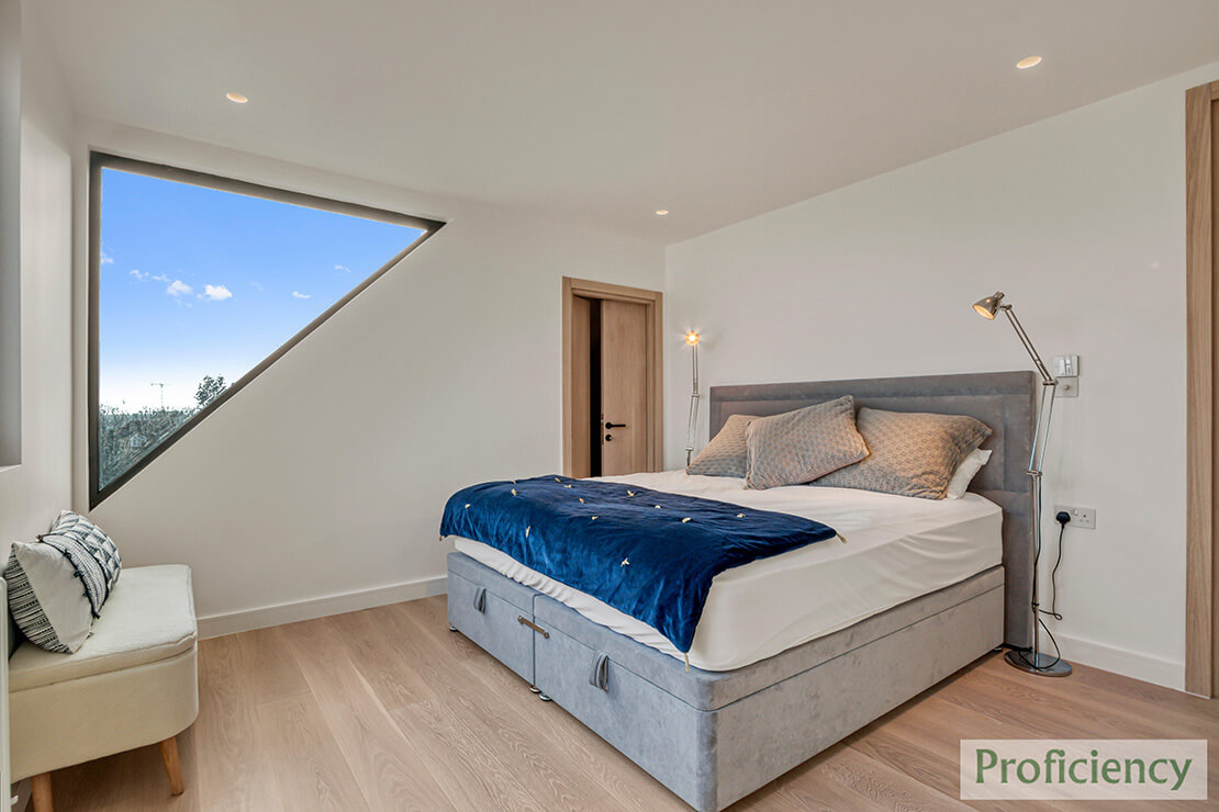 bedroom in a loft with large windows.