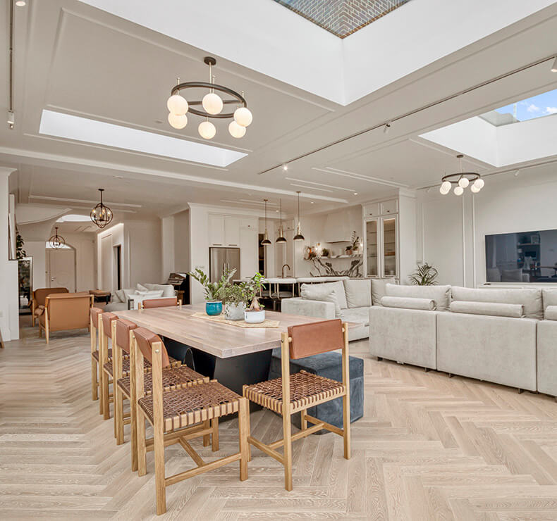 Modern domestic room with skylight and dark charcoal wood flooring, dark rust table and chairs design