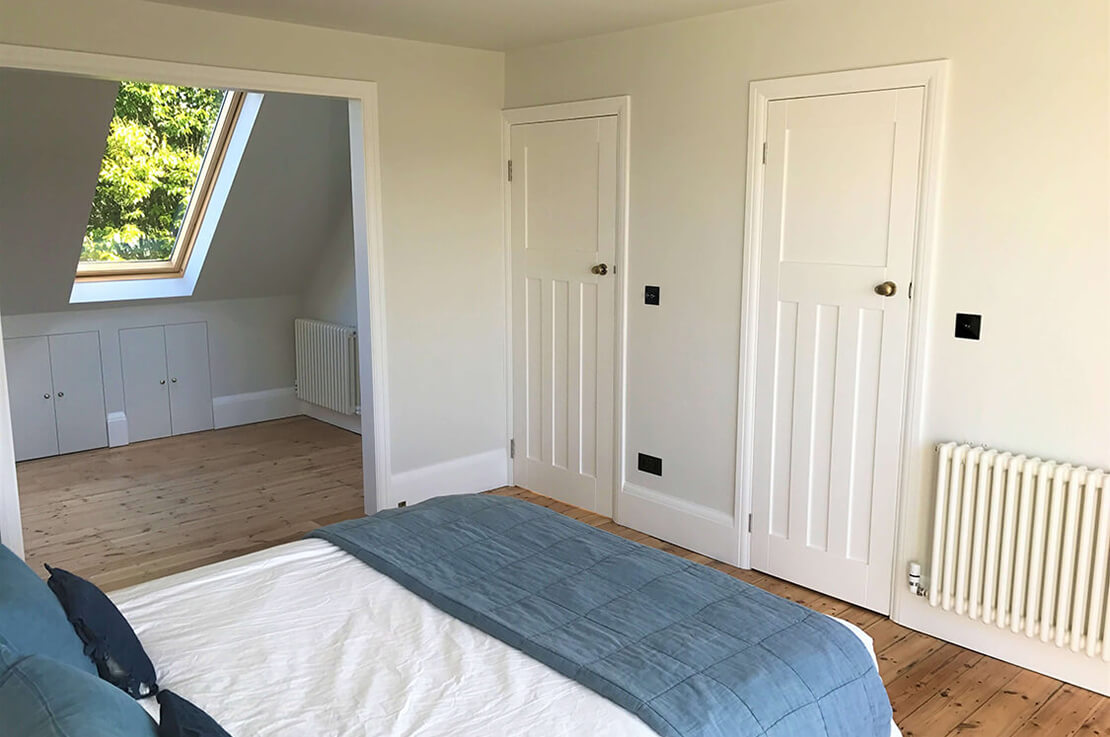 bedroom with white walls, wooden floorboards and skylight