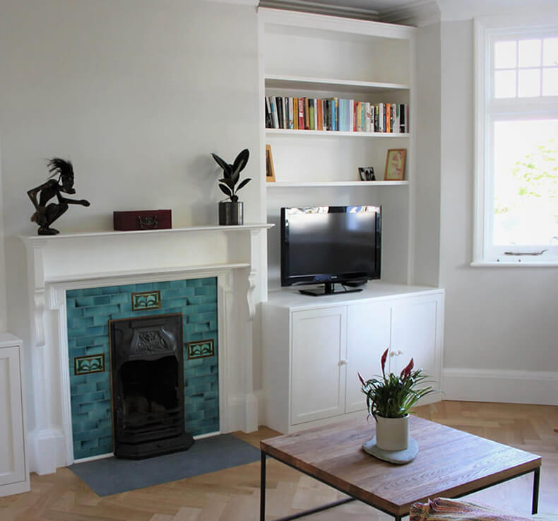 wooden floored lounge with fireplace, mantel and built-in shelves