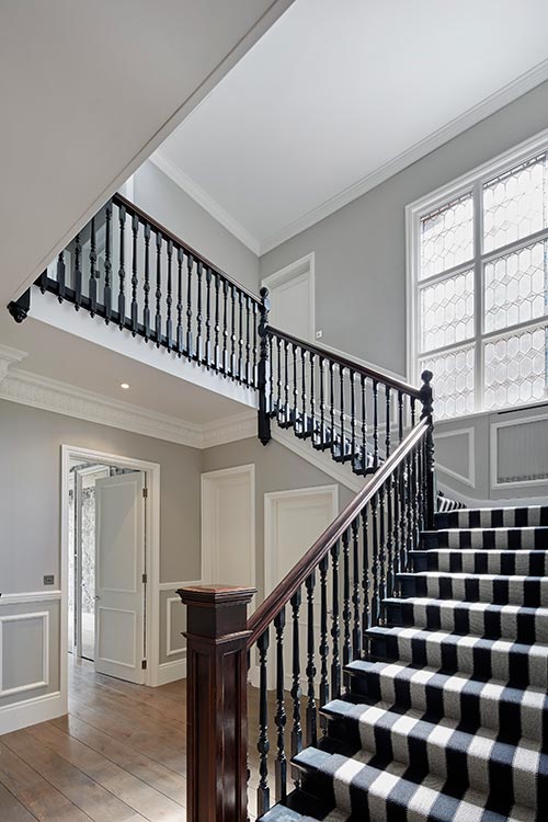 white and black striped carpeted staircase with black and wooden railing