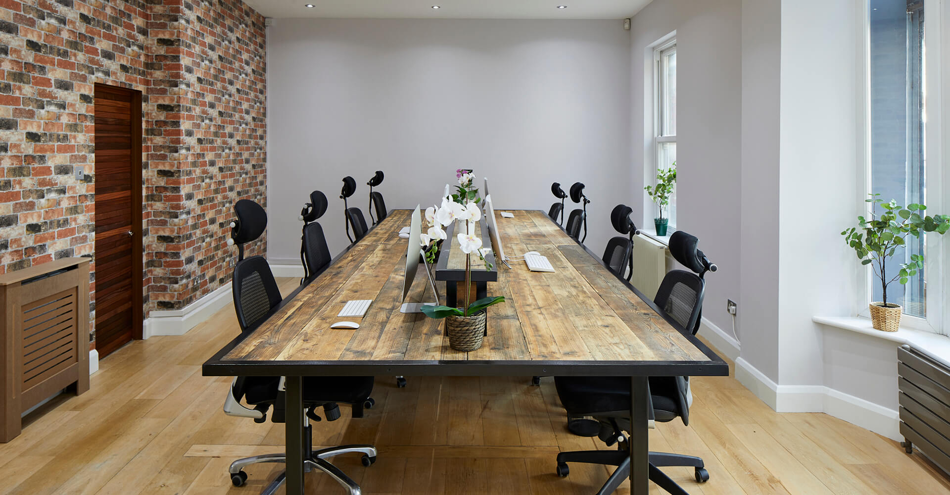 office with large modern wooden workstation and red brick interior wall