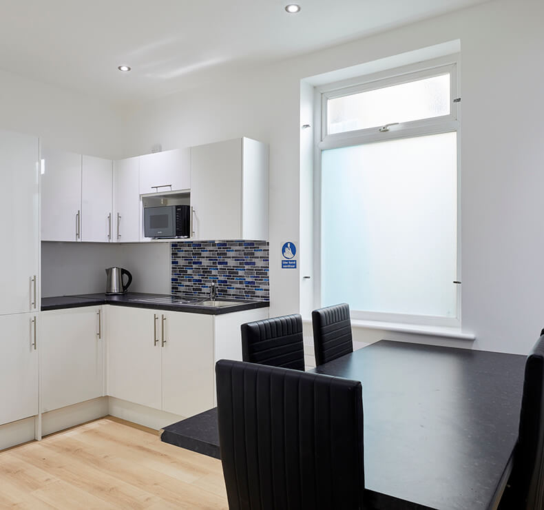 office kitchen with black dining set and white kitchen cabinets