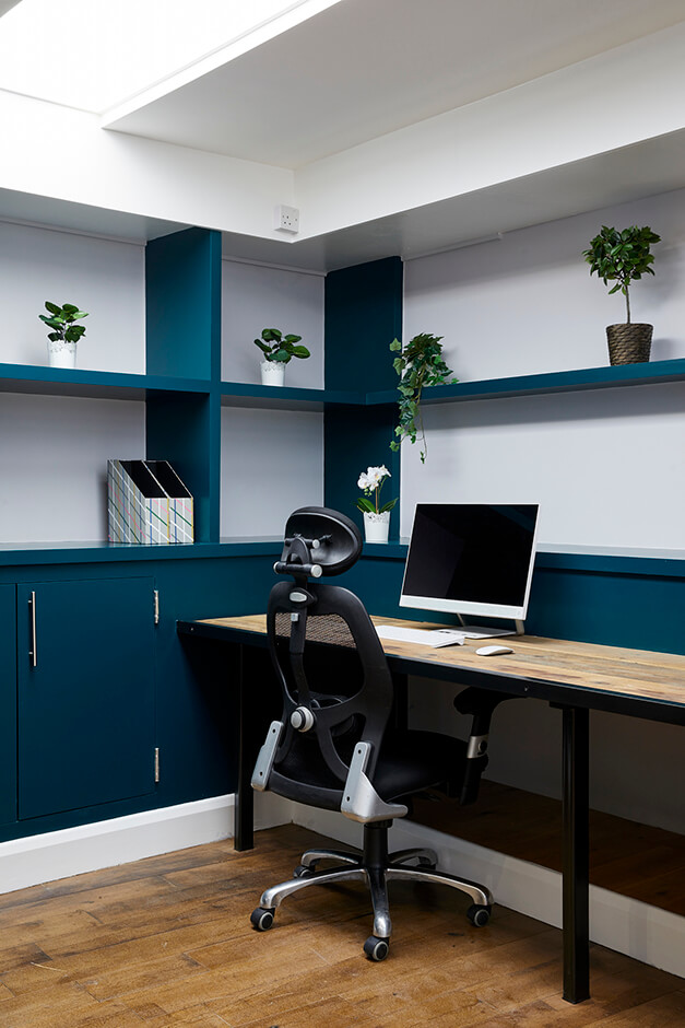 modern office with plants, wooden flooring, wooden desk and blue cabinets