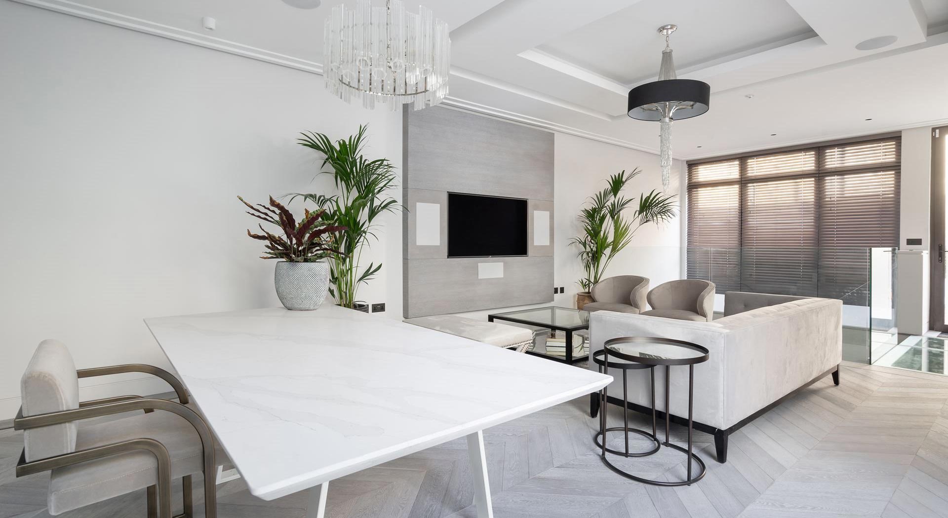 white and grey open plan dining room and lounge with wood flooring, drum chandelier and modern furniture