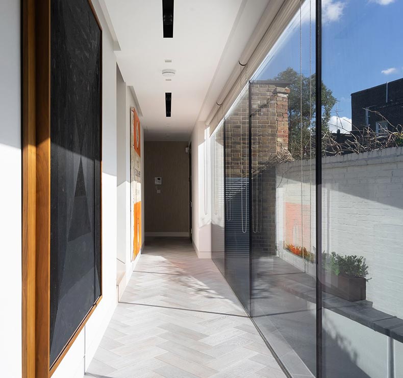 wooden floored hallway with white walls and large window view to exterior