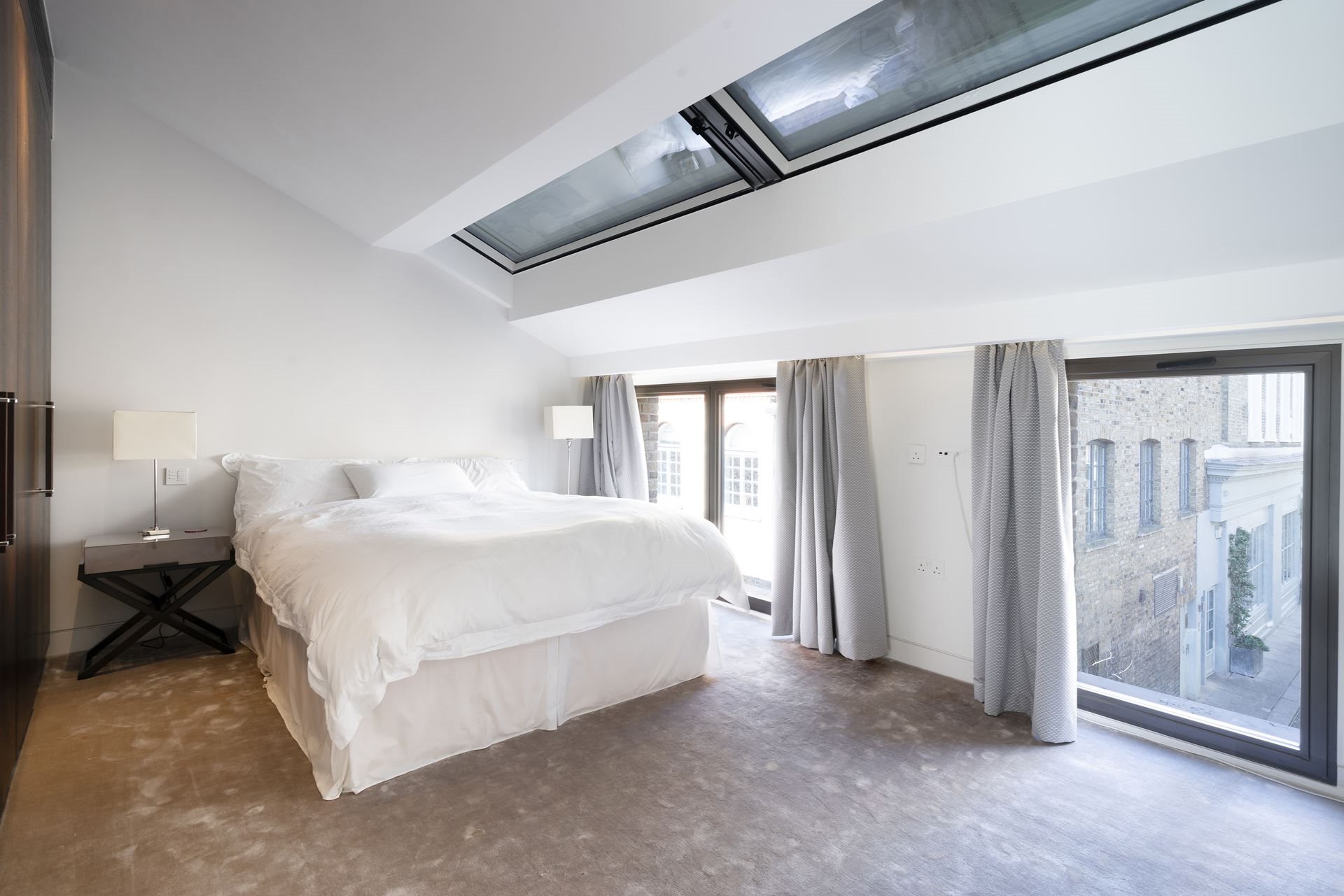 carpeted attic bedroom with large sliding windows and dark brown cabinets